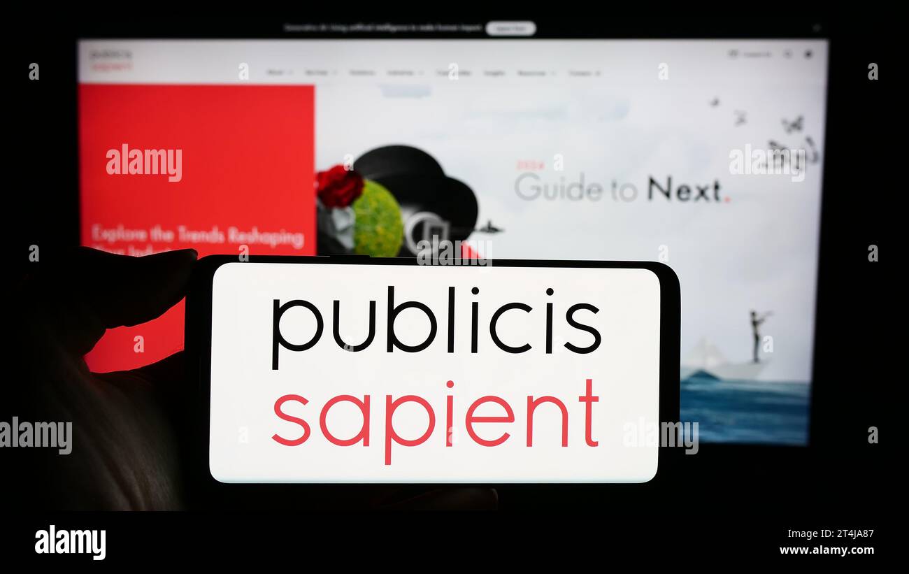 Personne détenant un téléphone mobile avec le logo de la société de conseil numérique Publicis Sapient en face de la page Web de l'entreprise. Concentrez-vous sur l'affichage du téléphone. Banque D'Images