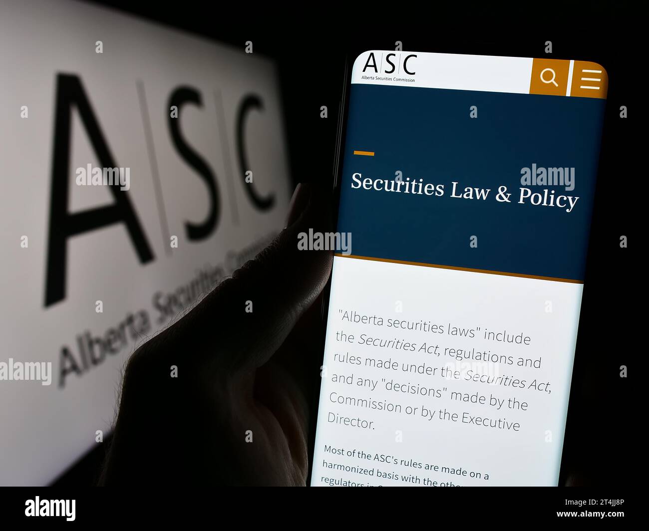 Personne détenant un téléphone mobile avec le site Web de l'organisme de réglementation Alberta Securities Commission (ASC) avec logo. Concentrez-vous sur le centre de l'écran du téléphone. Banque D'Images