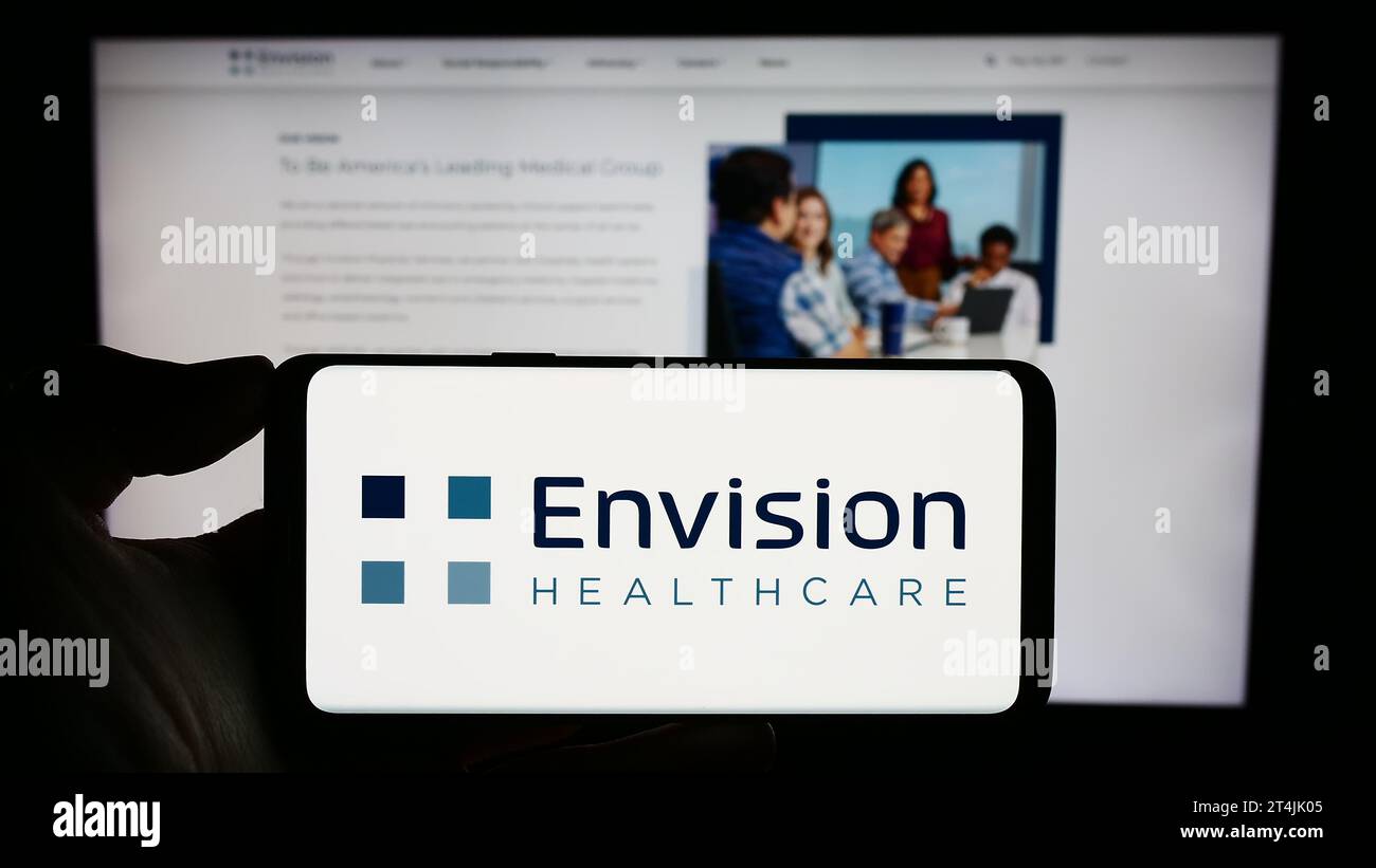 Personne tenant le téléphone portable avec le logo de la société hospitalière américaine Envision Healthcare en face de la page Web de l'entreprise. Concentrez-vous sur l'affichage du téléphone. Banque D'Images