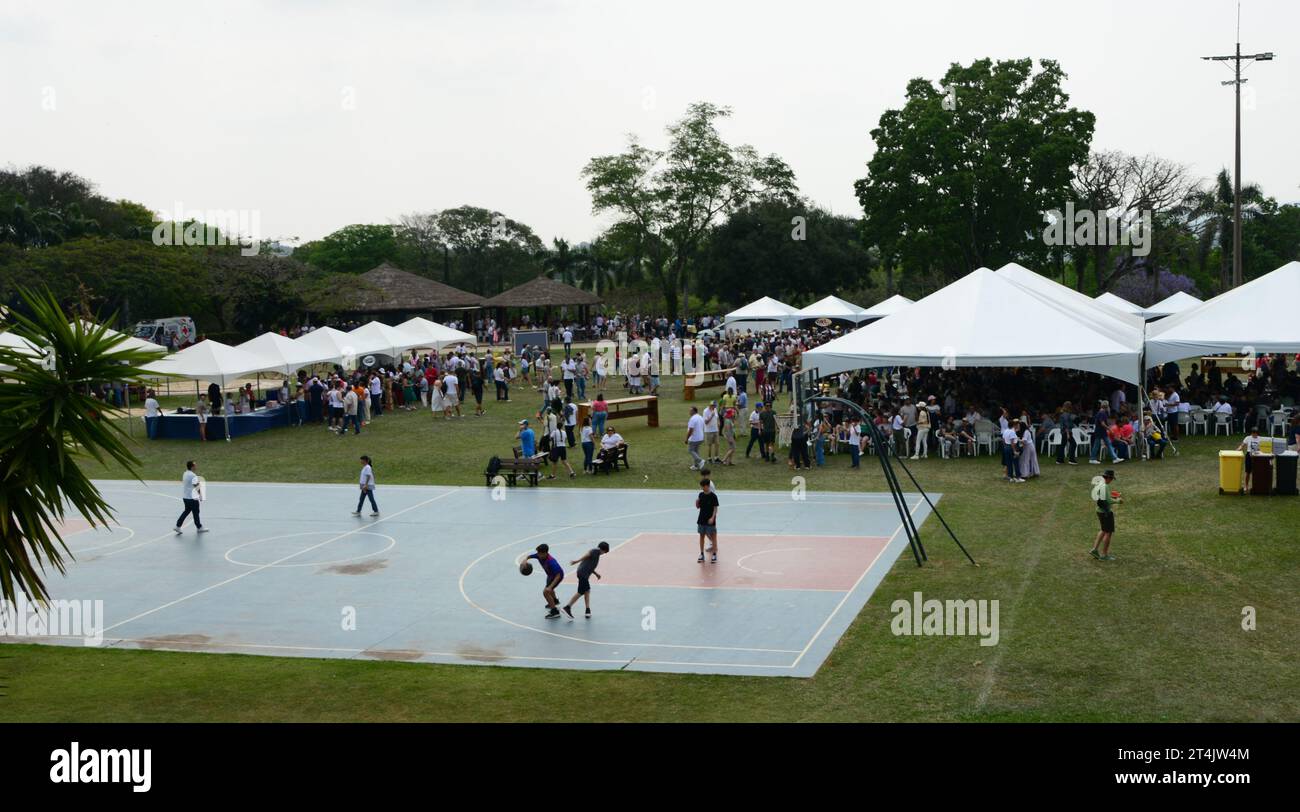 Garçons jouant au ballon sur un terrain de basket au premier plan avec des tentes blanches en arrière-plan Banque D'Images