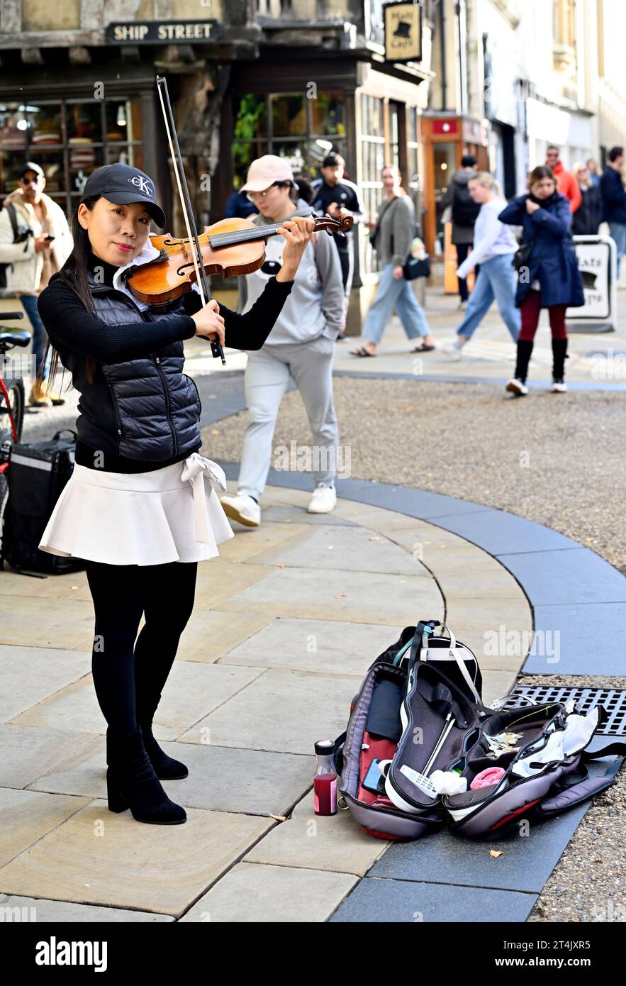Femme busker jouant du violon sur la rue de la ville avec sac pour la collection, Oxford, Royaume-Uni Banque D'Images