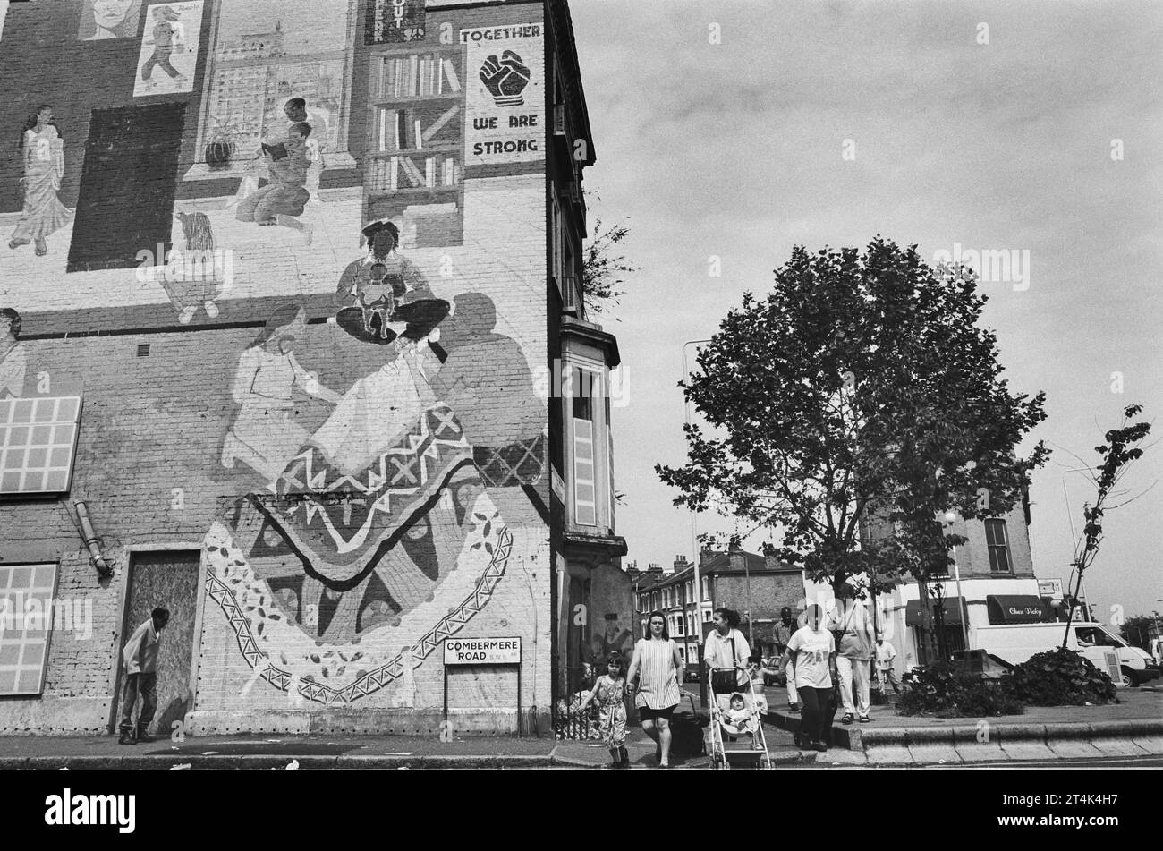 Une famille portugaise passant devant la fresque à l'ancien Black Women's Centre à Combermere/ Stockwell Roads, Brixton, Londres, Royaume-Uni Banque D'Images