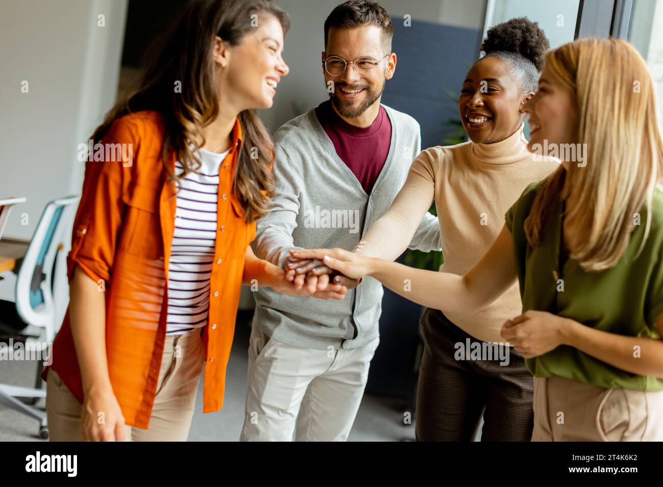 Une jeune équipe de start-up multiethnique tient la main ensemble au bureau moderne Banque D'Images