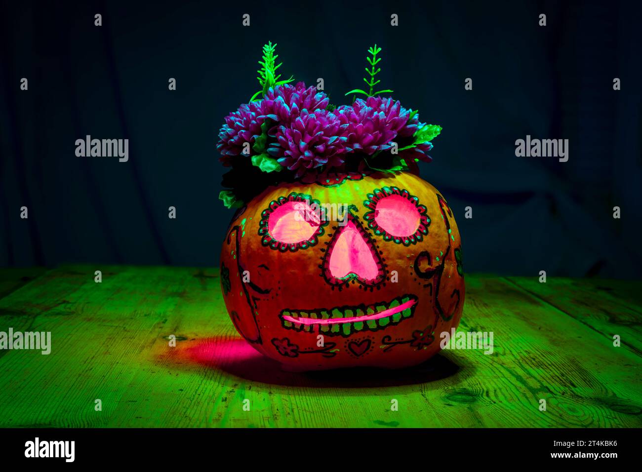 Citrouille d'Halloween décorée dans le style du jour des morts dans les mains sur une table en bois dans un environnement sombre et effrayant et coloré Banque D'Images