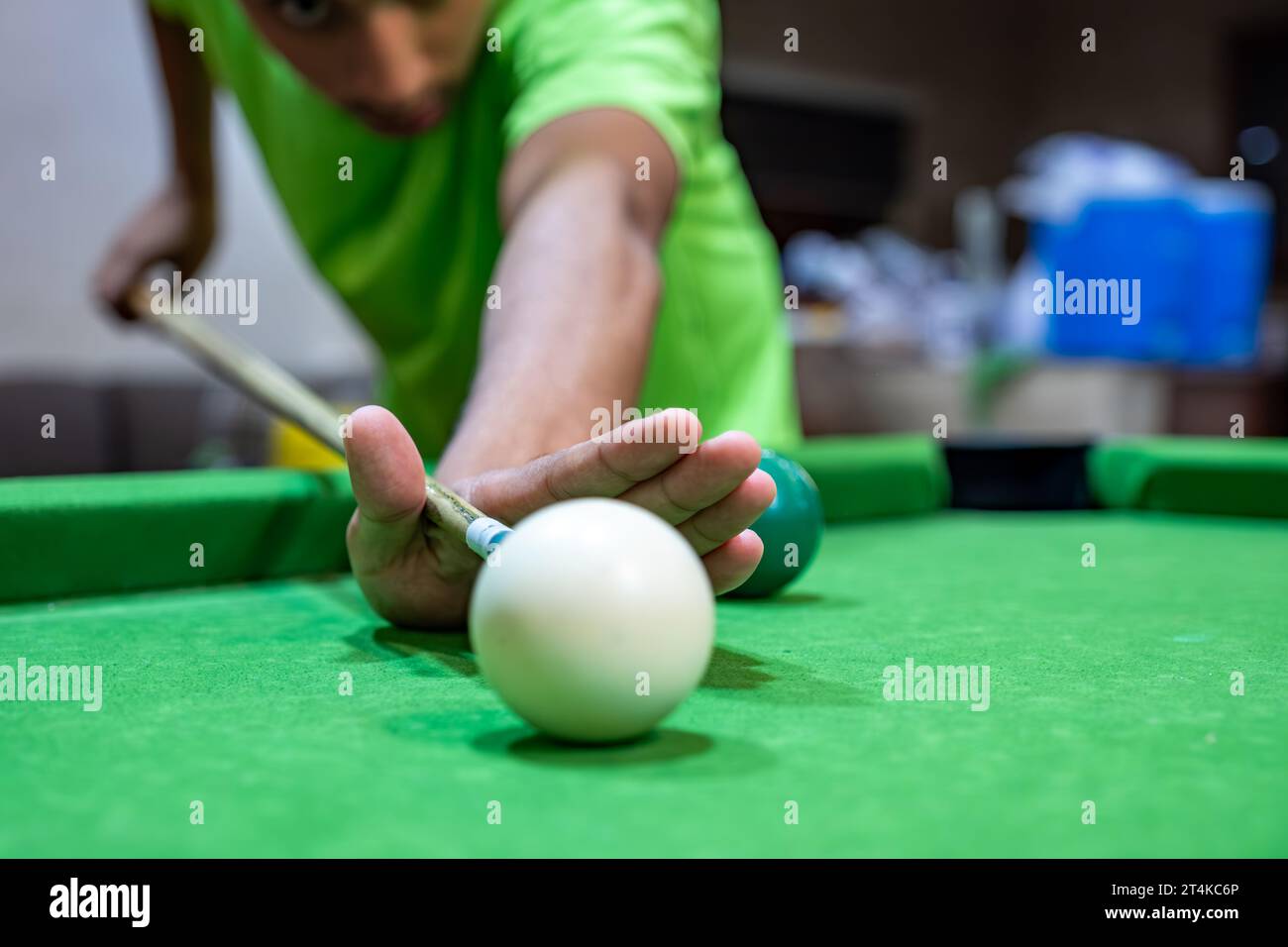 Jeune adulte Bearder mâle jouant au billard avec ses amis se concentrant sur la balle blanche pour le frapper avec la main musclée Banque D'Images