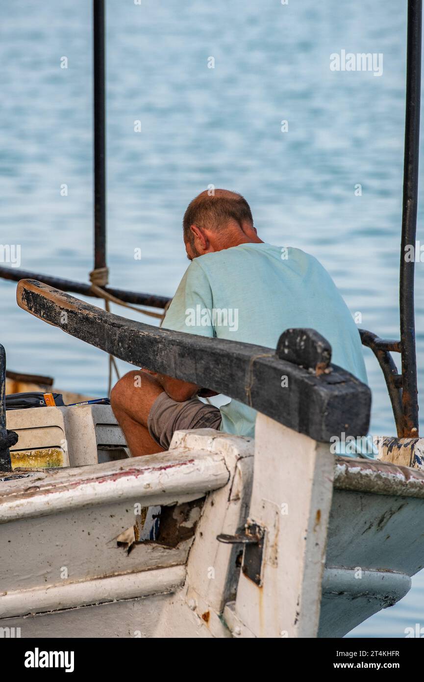 vieux pêcheur grec assis sur un bateau de pêche traditionnel dans le port maritime ionien de zakynthos ou la ville de zante en grèce, Banque D'Images