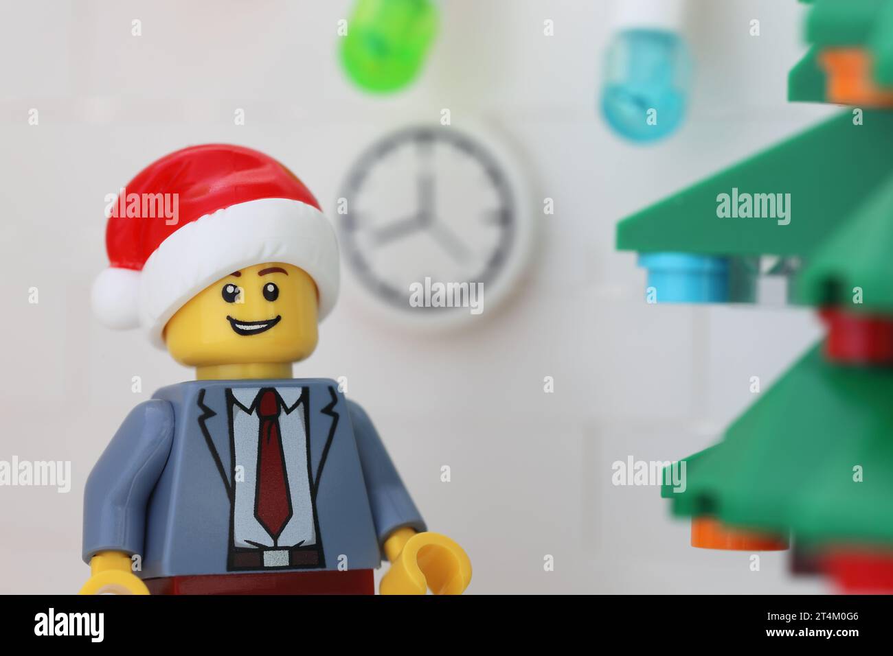 Tambov, Fédération de Russie - 31 octobre 2023 Une minifigurine d'homme d'affaires Lego portant un chapeau de Père Noël et debout à côté d'un arbre de Noël dans son bureau Banque D'Images