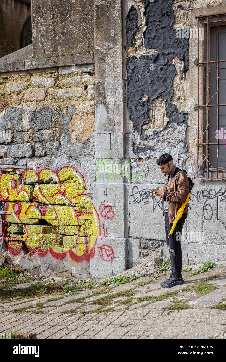 TourGuide avec parapluie jaune sur téléphone portable à Porto, Portugal le 21 octobre 2023 Banque D'Images