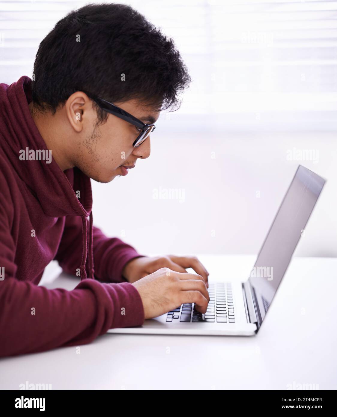 Faire la tâche efficacement. un beau jeune homme travaillant sur son ordinateur portable dans un bureau. Banque D'Images