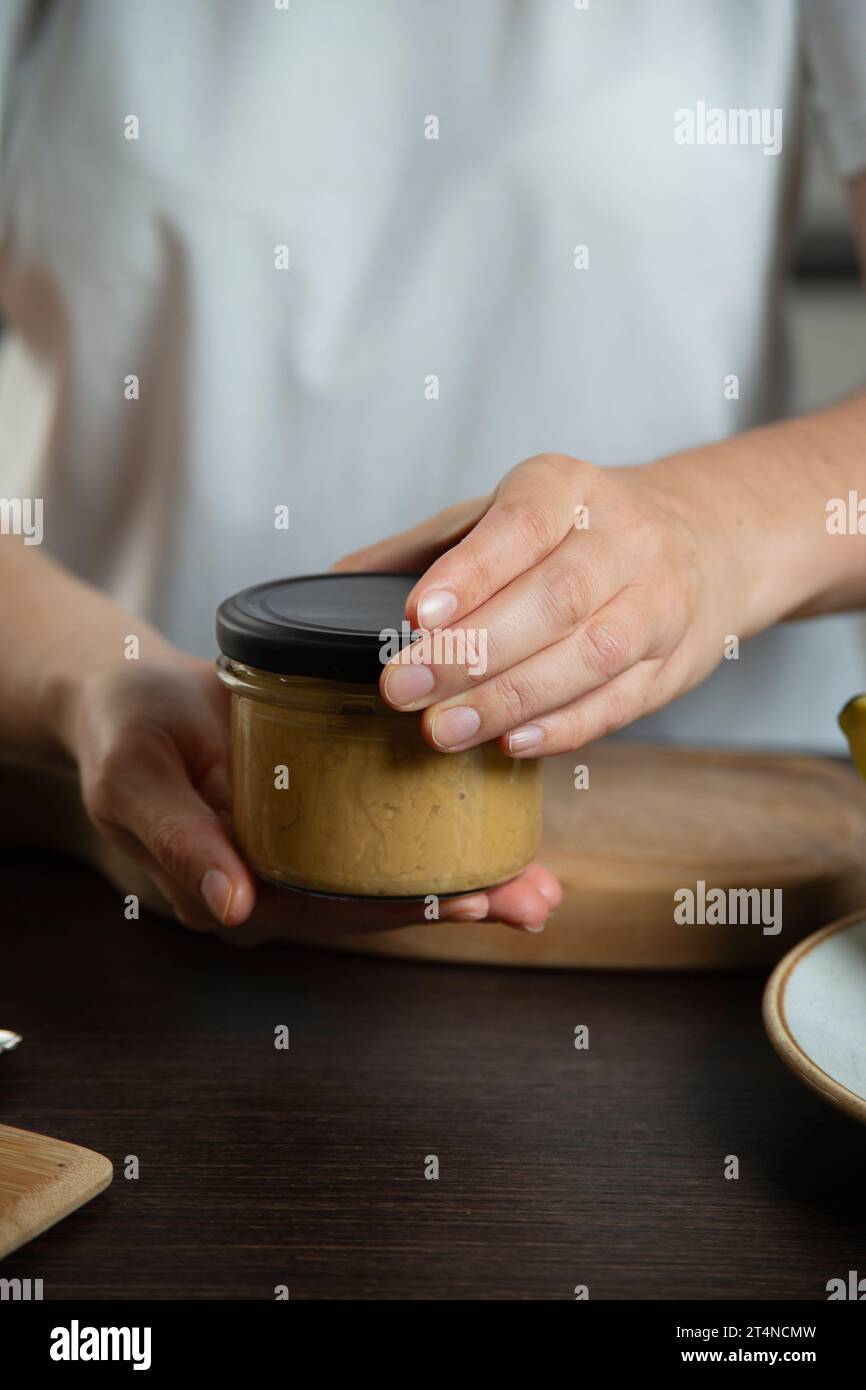 Beurre de cacahuète dans les mains de femme dans la cuisine. Banque D'Images