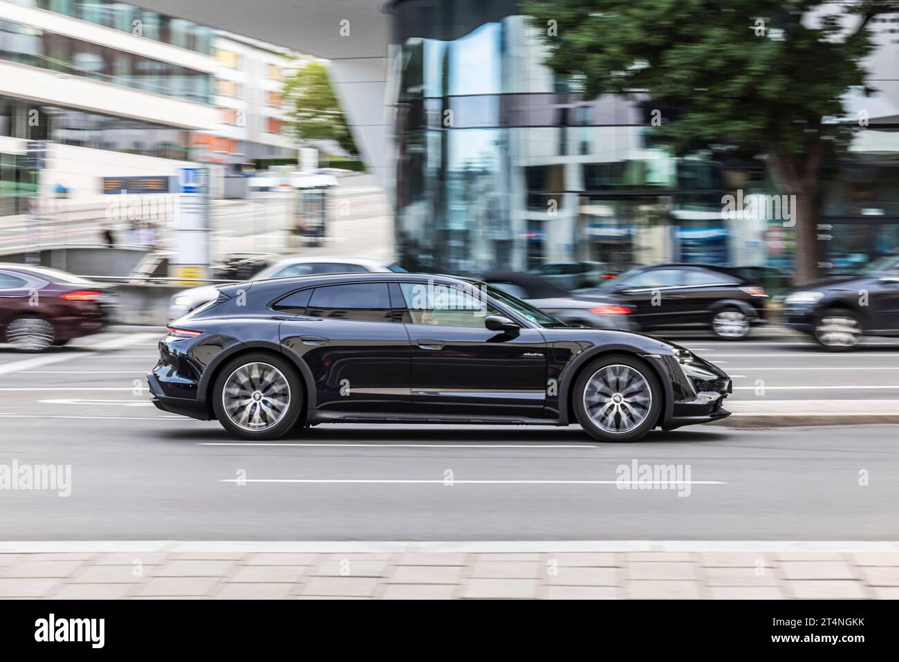 Voiture de nuit devant un environnement urbain à l'architecture moderne, pull-along, Porsche Taycan GTS Sport Turismo, Stuttgart, Baden-Wuerttemberg Banque D'Images