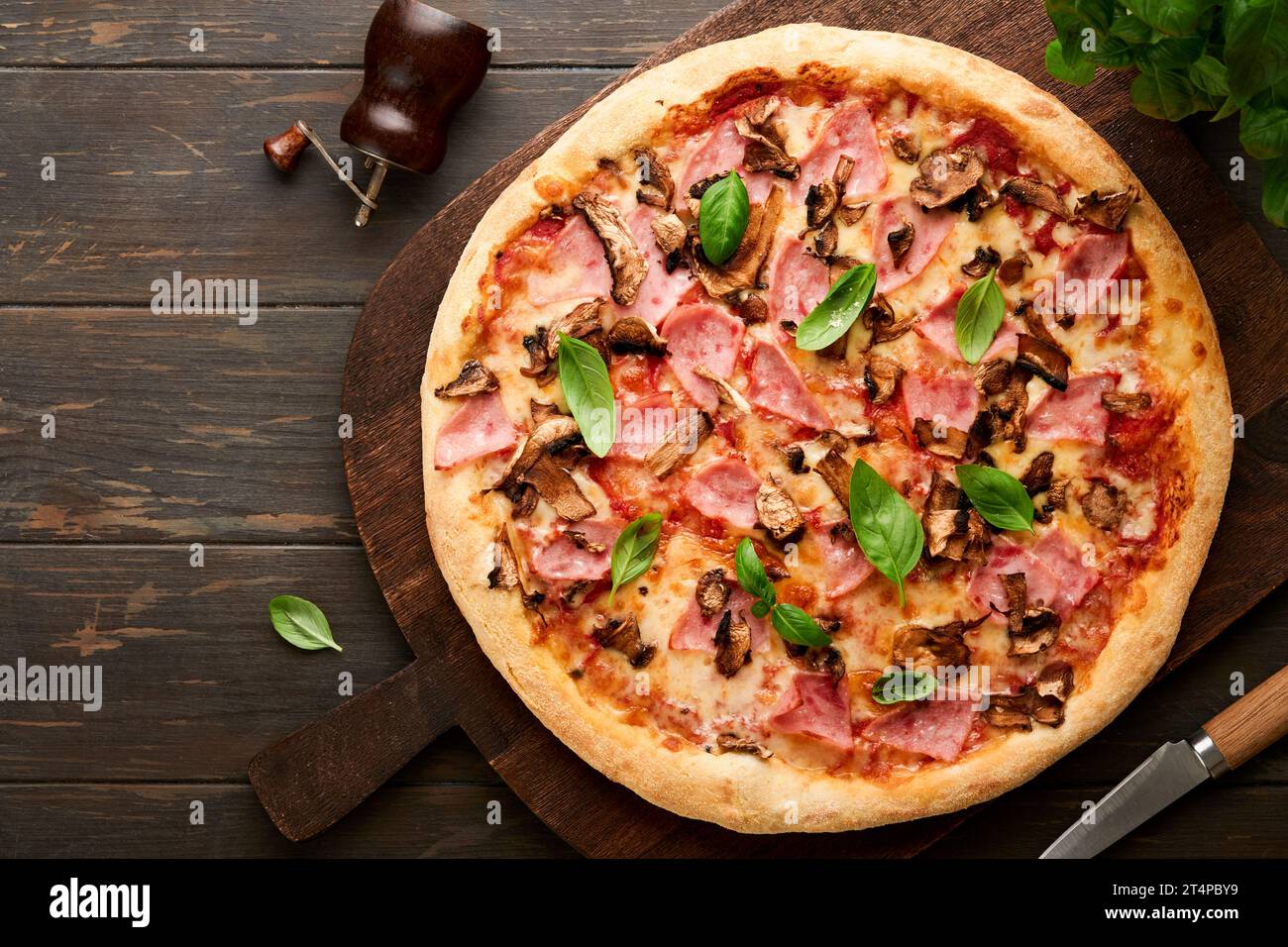 Pizza. Pizza traditionnelle au bacon avec jambon, champignons, concombre mariné et fromage et ingrédients de cuisson tomates basilic sur fond de table en bois. IT Banque D'Images