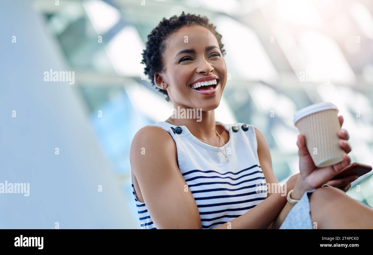 Shes sa propre patronne dame et elle adore ça. une jeune femme d'affaires attrayante riant tout en étant assise dans un lieu de travail moderne. Banque D'Images