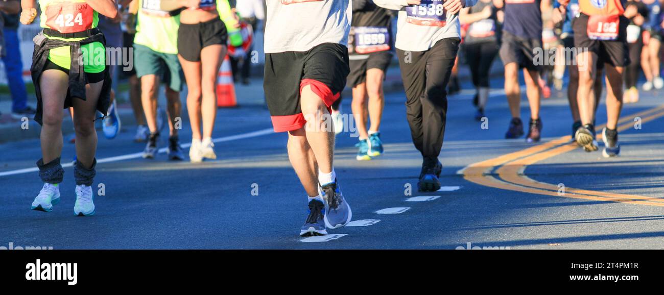 Le bas du corps de nombreux coureurs qui courent dans un marathon sur une route à long Island. Banque D'Images