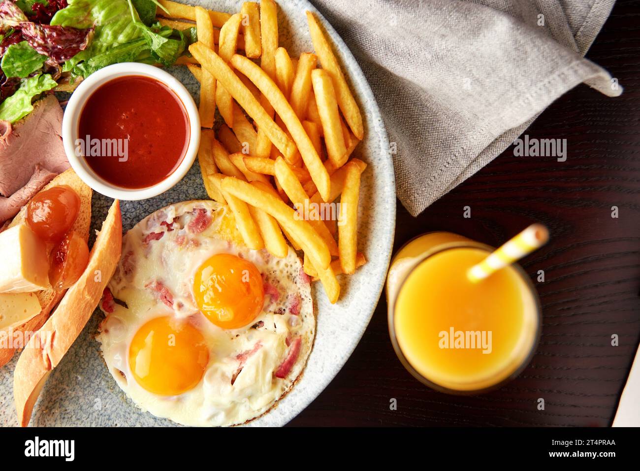 Petit-déjeuner anglais complet avec jambon, salade, œufs de caille frits avec bacon, pain grillé avec fromage et sauce tomate servis avec un verre de jus d'orange. Banque D'Images