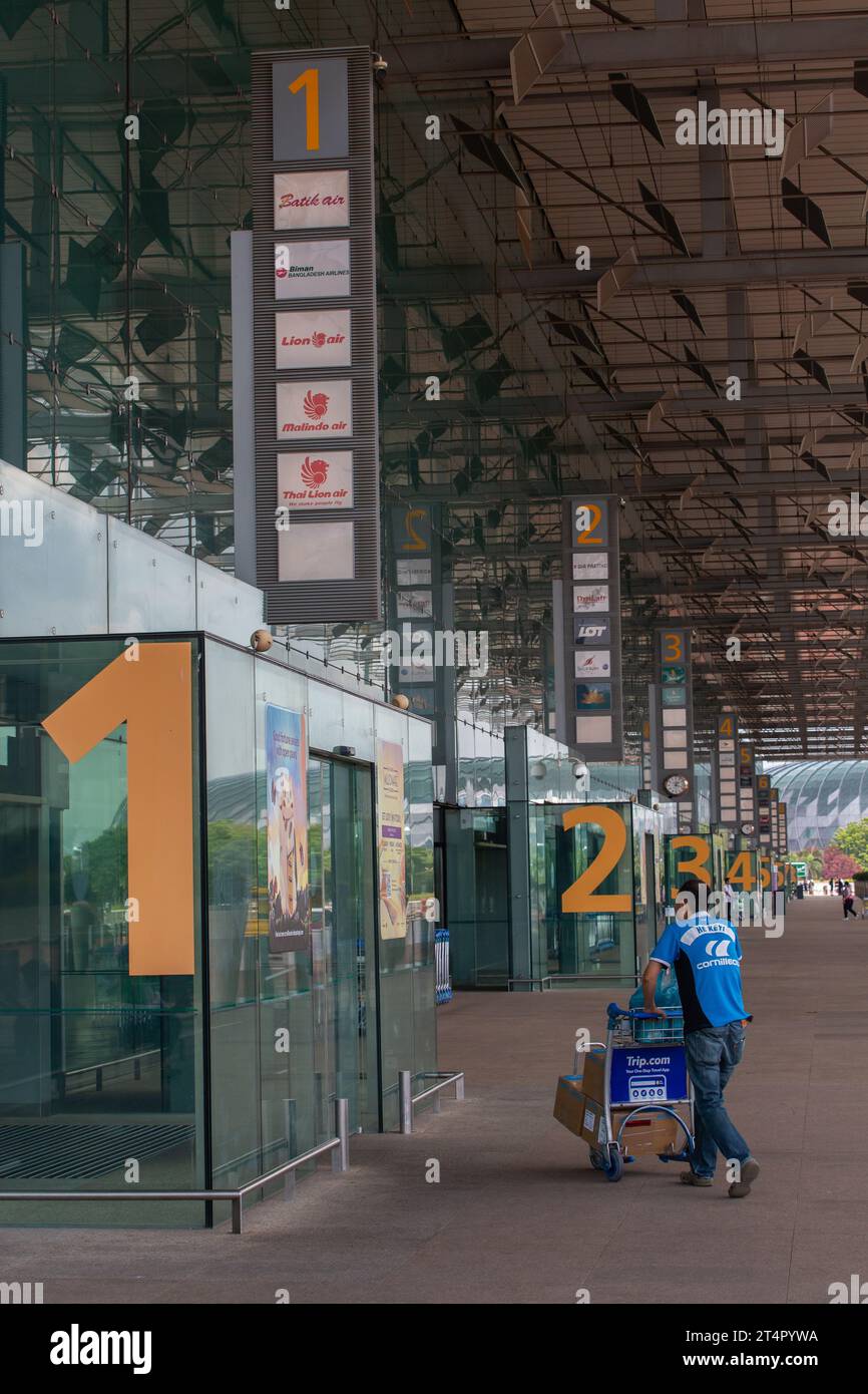 Vue verticale d'un passager poussant un chariot dans l'entrée de la zone de départ au terminal 3 de l'aéroport de Changi. Singapour Banque D'Images