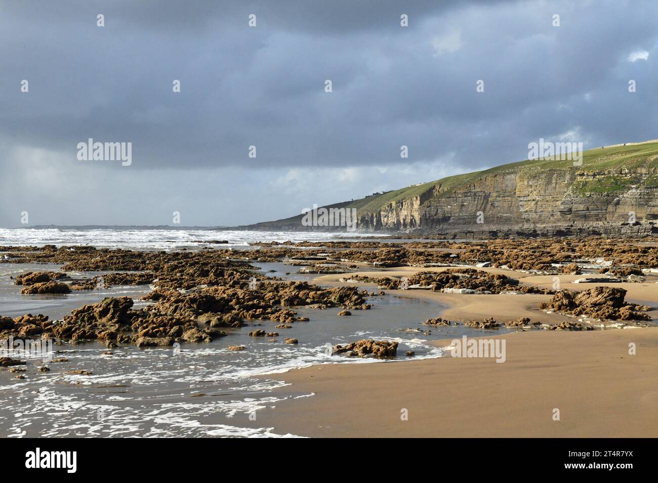 Dunraven Bay avec des falaises derrière et des rochers, des vagues et du sable en face par une journée ensoleillée de novembre sur la Glamorgan Heritage Coast en Galles du Sud Banque D'Images