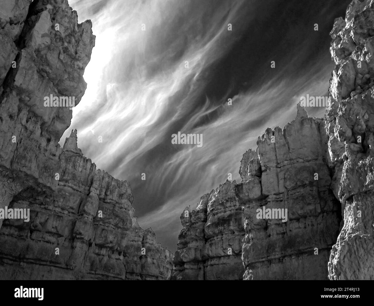 Vue sinistre en noir et blanc des nuages de cirrus avec les hautes falaises calcaires et les hoodoos de Bryce Canyon au premier plan. Banque D'Images