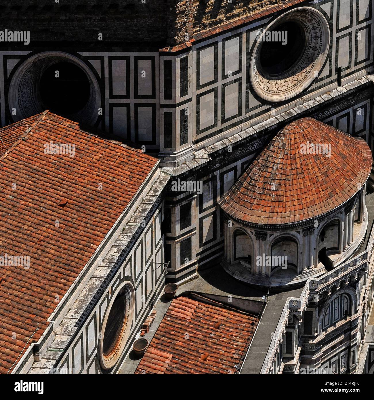 Duomo di Firenze, Toscane, Italie : toits de tuiles rouges et passerelle, avec oculi et marbre blanc. En haut de l’image se trouve une partie de la base en briques brutes laissée sur sept côtés du dôme octogonal de la cathédrale, conçu par Filippo Brunelleschi (1377 - 1446). Banque D'Images