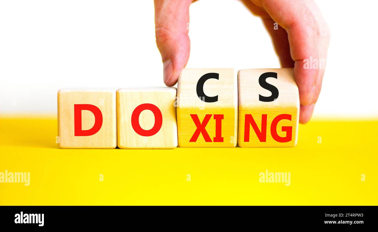 Symbole Docs ou doxing. Mots conceptuels Docs Doxing sur bloc de bois. Belle table jaune fond blanc. Main d'homme d'affaires. Documents d'affaires ou doxing c Banque D'Images