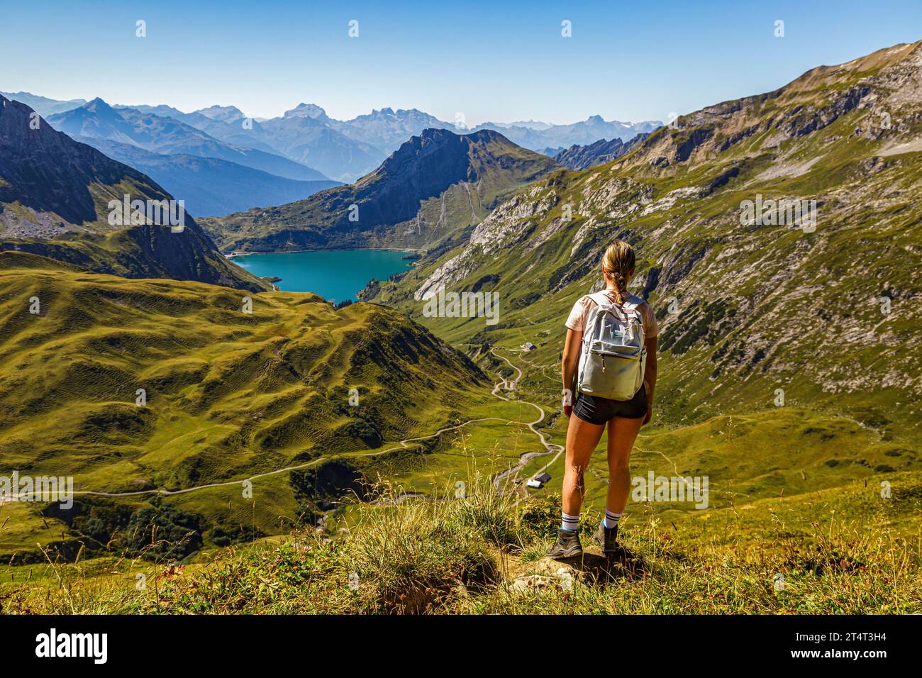 Eine junge Frau steht an einem Wanderweg auf einem Berg und schaut auf den Spullersee in Vorarlberg Lech Östereich Banque D'Images