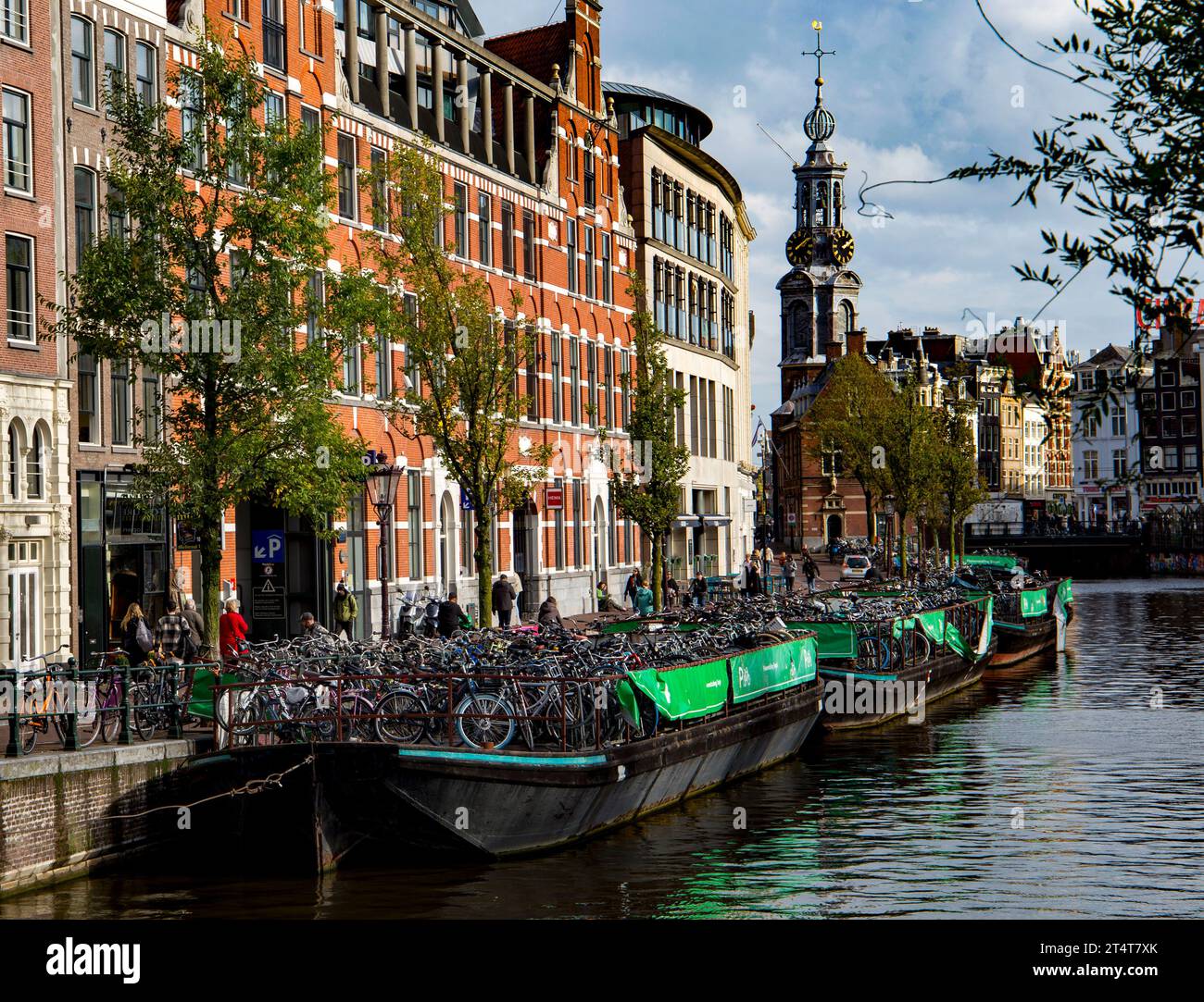 Vue panoramique sur le canal d'Amsterdam avec des vélos garés le long du pont, des bâtiments historiques et des péniches pleines de vélos Banque D'Images