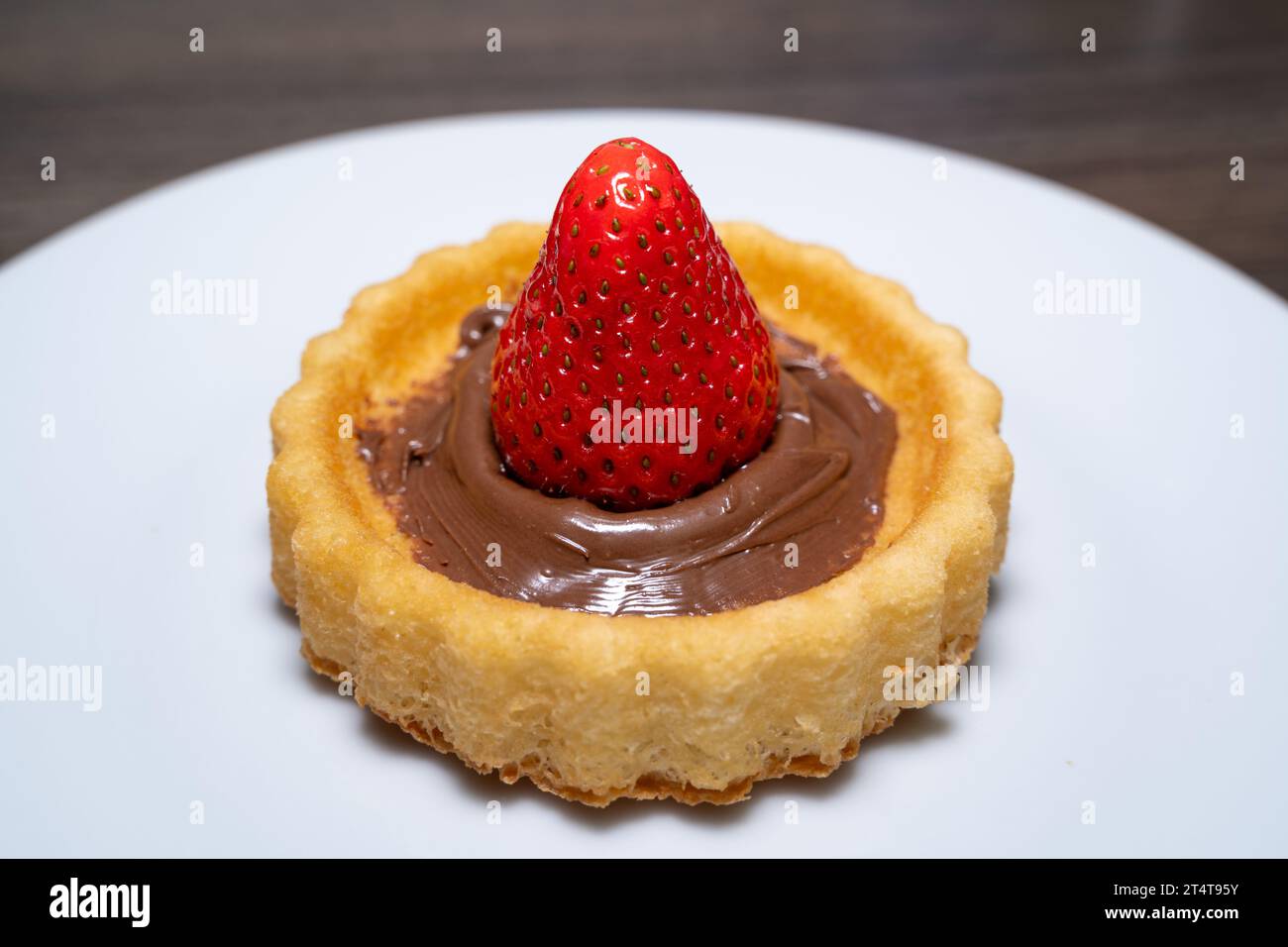 Petit gâteau avec de la crème au chocolat et une fraise Banque D'Images