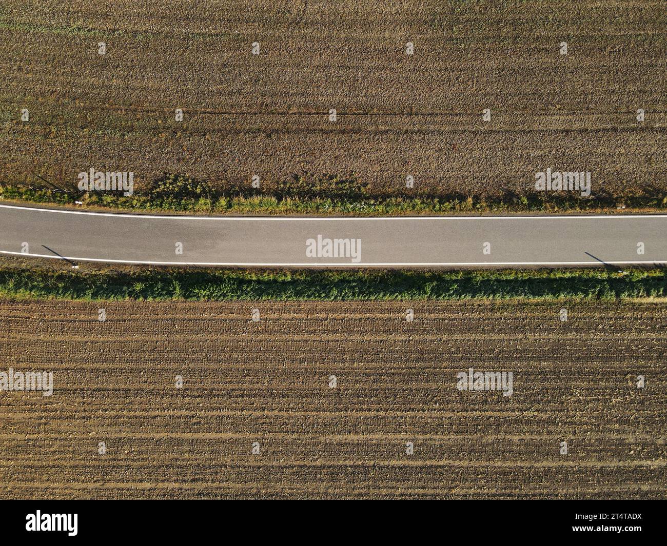 Vue aérienne d'une route entre champs agricoles bruns avec sol à la campagne Banque D'Images