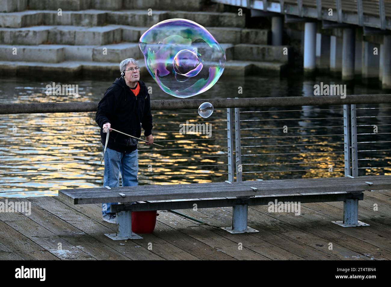 Homme soufflant de grosses bulles de savon, False Creek, Vancouver, Colombie-Britannique, Canada Banque D'Images