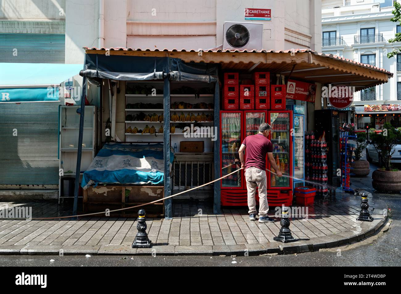 Propriétaire du magasin dédié d'Istanbul qui épice dans la rue devant son magasin d'angle animé, orné de fruits colorés et de boissons rafraîchissantes. Banque D'Images