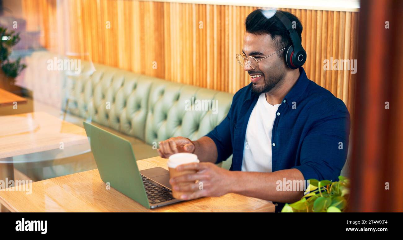 Homme heureux dans le café avec écouteurs, ordinateur portable et travail à distance, lecture de courrier électronique et Internet dans le restaurant. Ordinateur, freelance et copywriter dans Banque D'Images