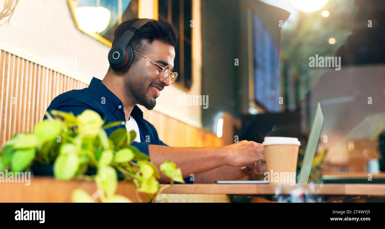 Homme heureux dans le café avec des écouteurs, taper sur un ordinateur portable et le travail à distance, lire le courrier électronique et le Web dans le restaurant. Ordinateur, freelance sourire et rédacteur en chef Banque D'Images