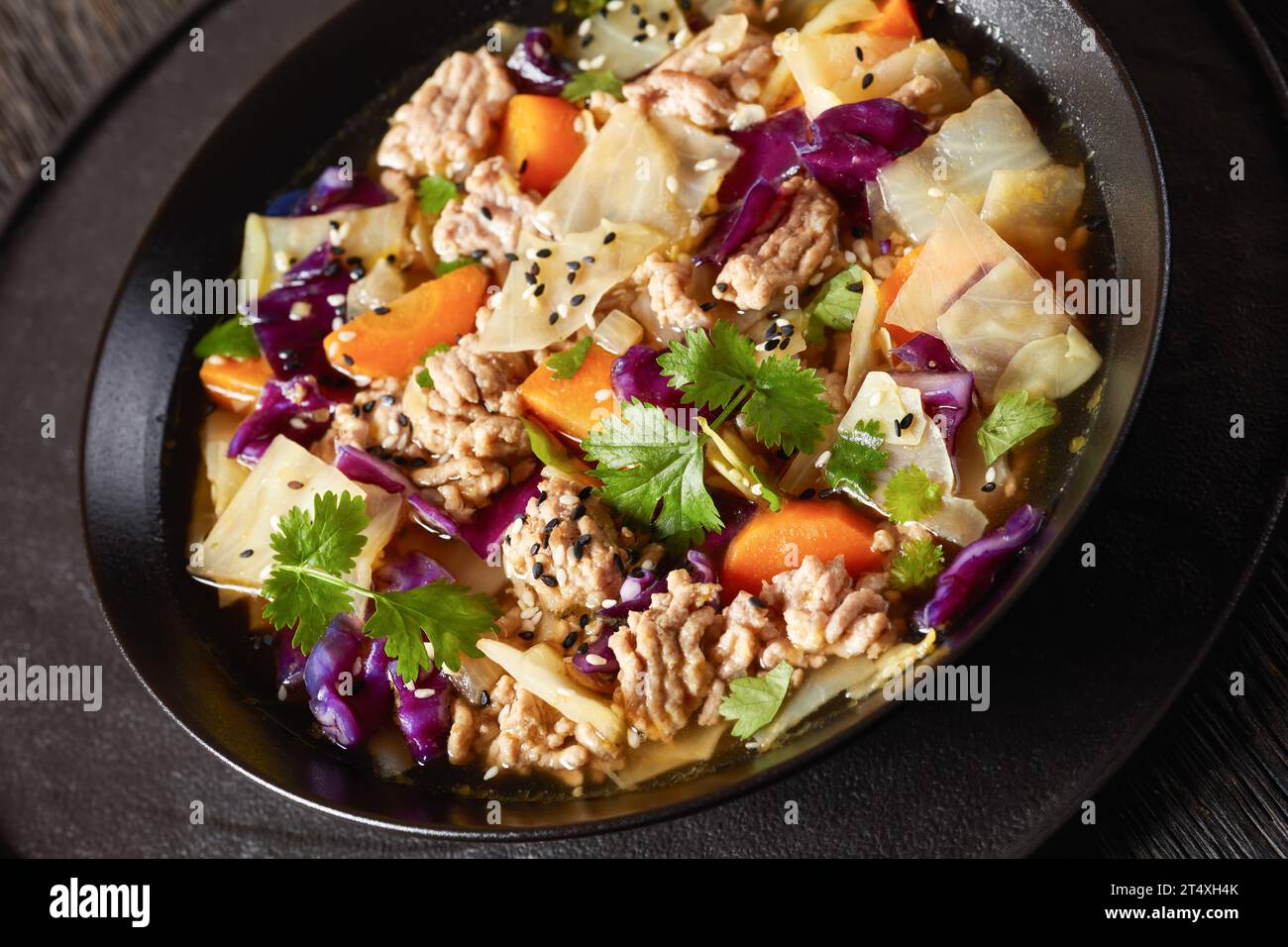 soupe au chou roulé aux œufs avec du porc haché et des légumes dans un bol noir sur une table en bois sombre, cuisine asiatique, gros plan, angle hollandais Banque D'Images