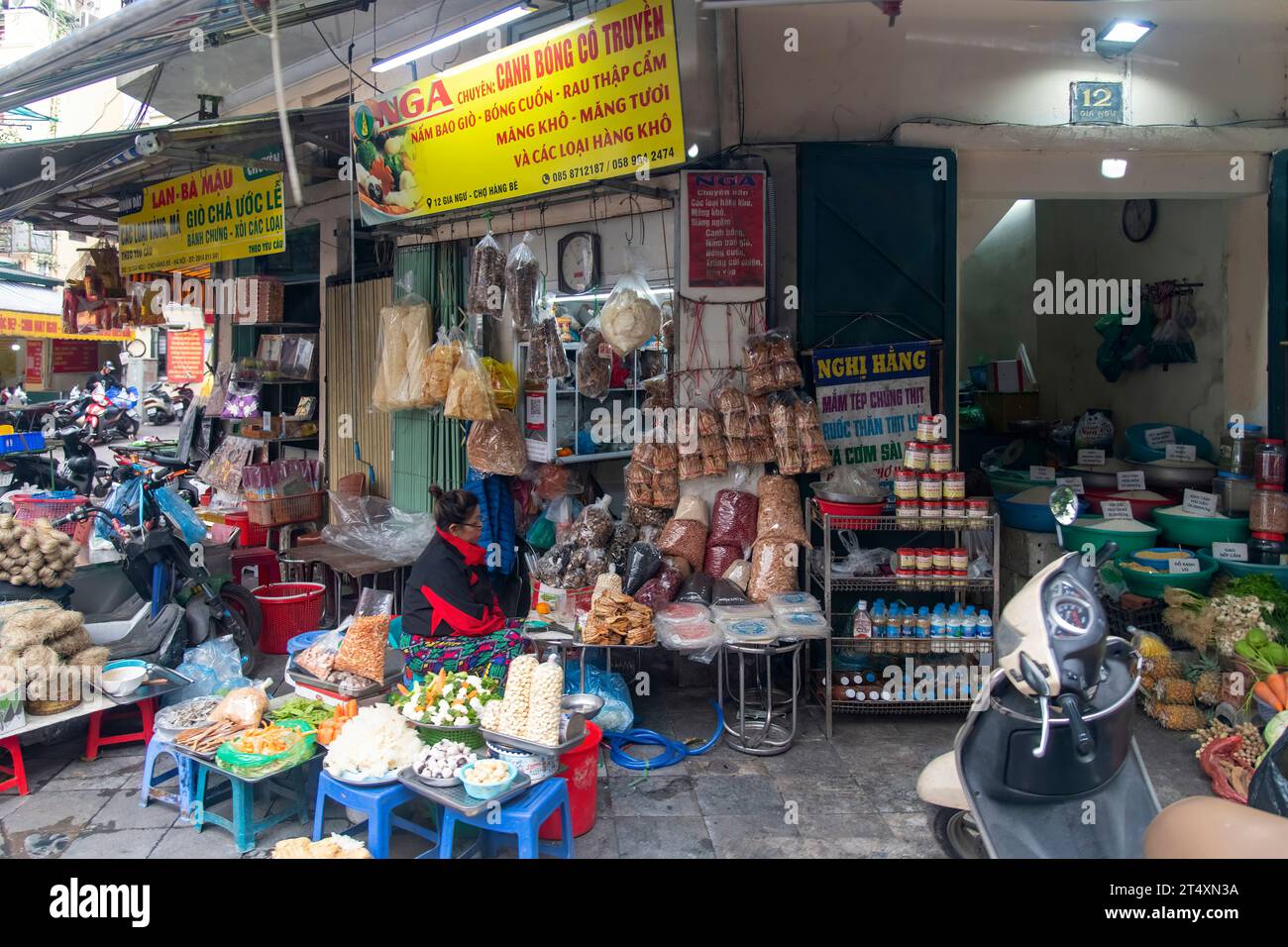 Hanoi, Vietnam-30 mars 2023 ; vendeuse de rue assise sur un tabouret de son magasin dans l'un des quartiers de la ville vendant des produits alimentaires de base Banque D'Images
