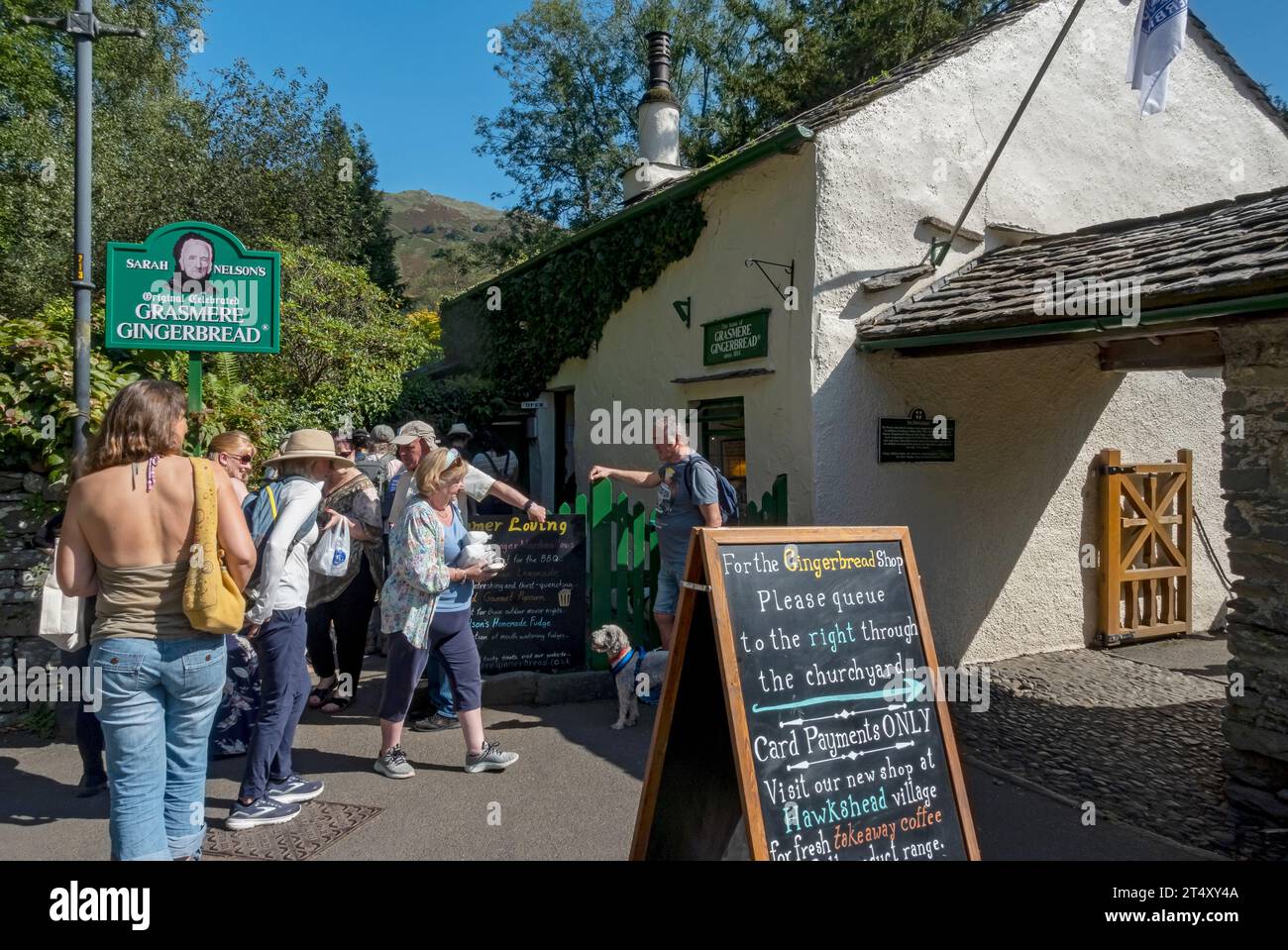 Touristes visiteurs personnes faisant la queue devant Sarah Nelson's Gingerbread cottage shop en été Grasmere Cumbria Angleterre Royaume-Uni GB Grande-Bretagne Banque D'Images