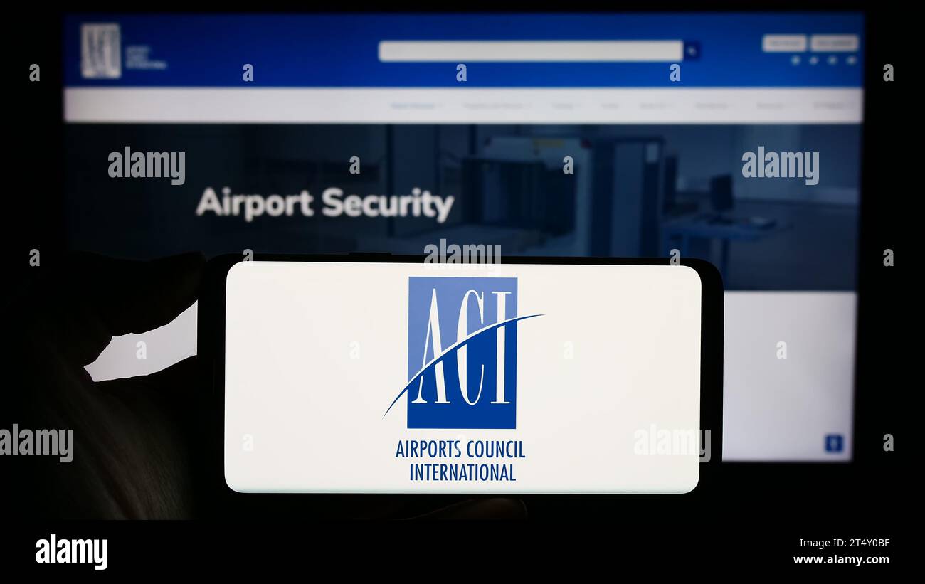 Personne tenant un téléphone cellulaire avec le logo de l'organisation Airports Council International (ACI) devant la page Web. Concentrez-vous sur l'affichage du téléphone. Banque D'Images