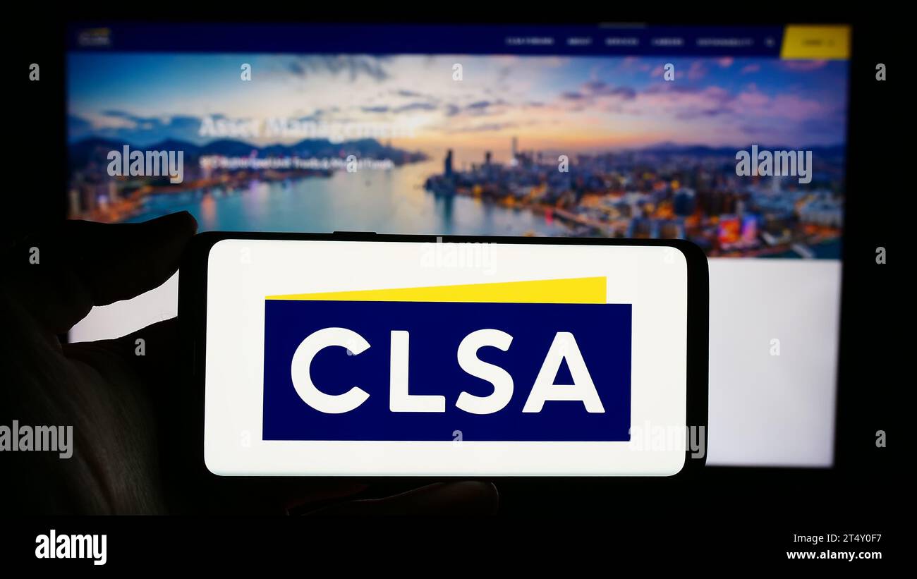 Personne détenant un téléphone portable avec le logo de la société d'investissement de Hong Kong CLSA Ltd. Devant la page Web de l'entreprise. Concentrez-vous sur l'affichage du téléphone. Banque D'Images
