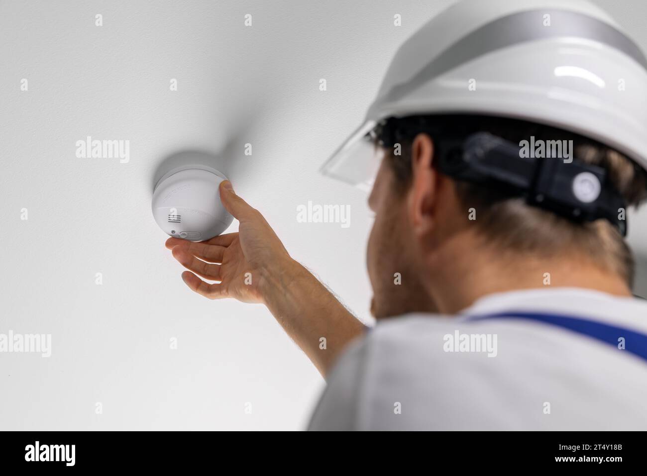 travailleur installant un détecteur de fumée photoélectrique sur le plafond de la maison. système de sécurité domestique et d'alarme incendie Banque D'Images