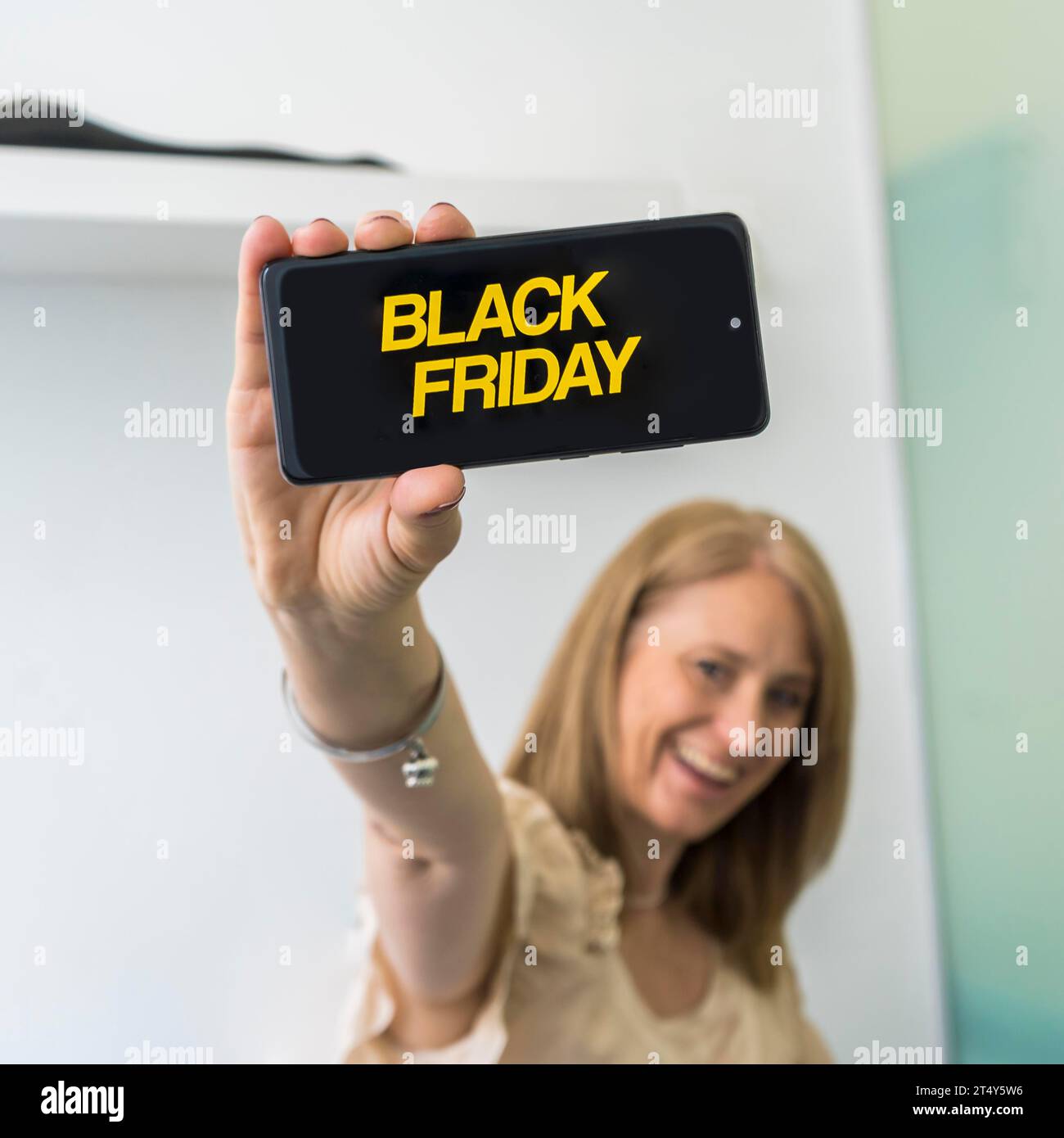 Une femme montrant un smartphone avec une publicité Black Friday à l'écran Banque D'Images