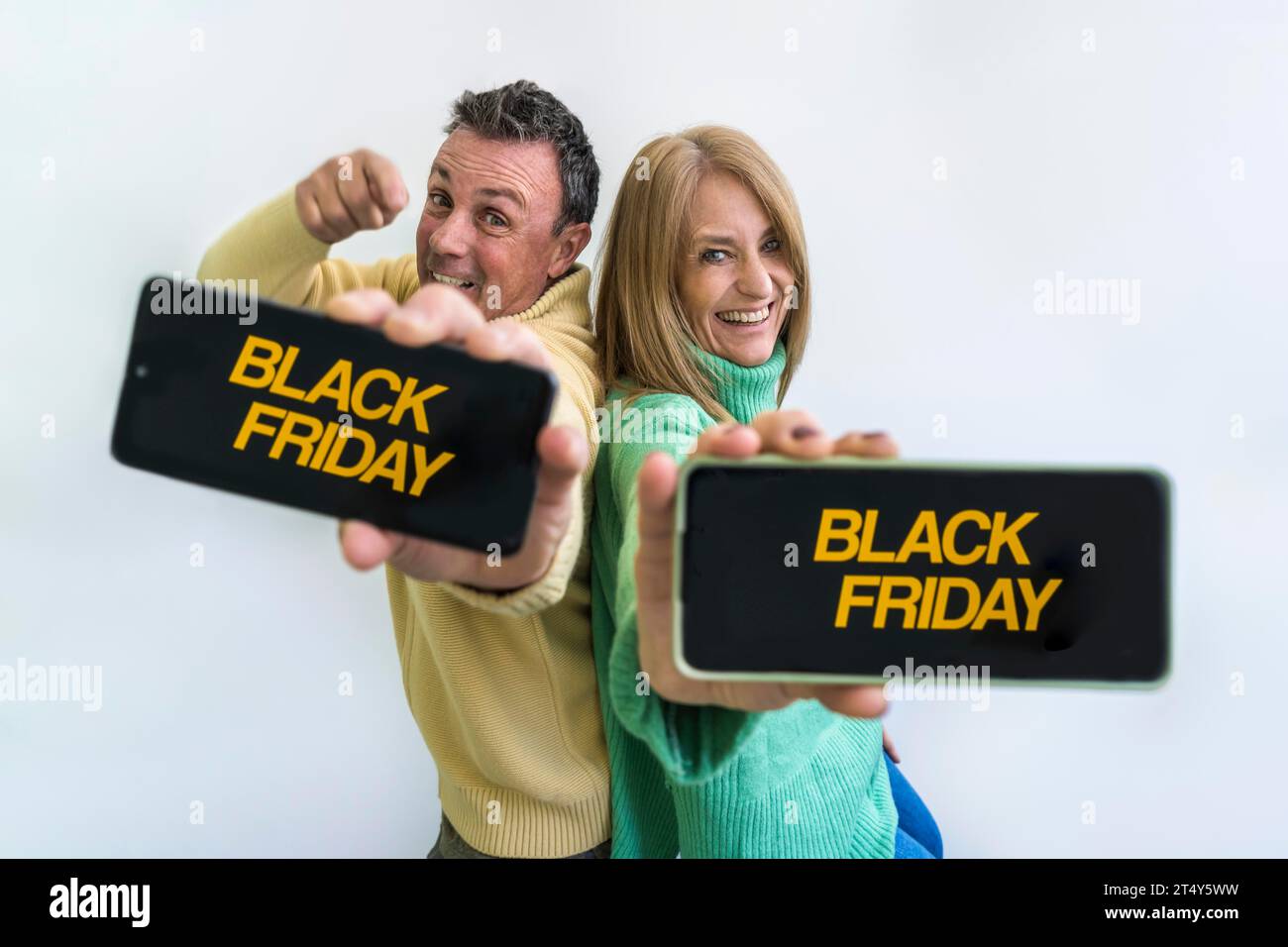 Couple heureux tenant des téléphones intelligents avec la publicité Black Friday sur les écrans Banque D'Images