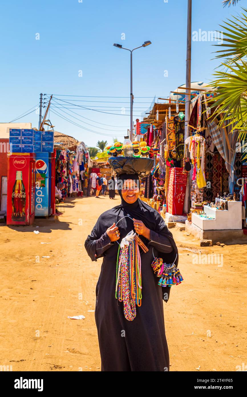 Femme égyptienne avec des souvenirs dans le célèbre village nubien. Assouan, Égypte – 17 octobre 2023 Banque D'Images