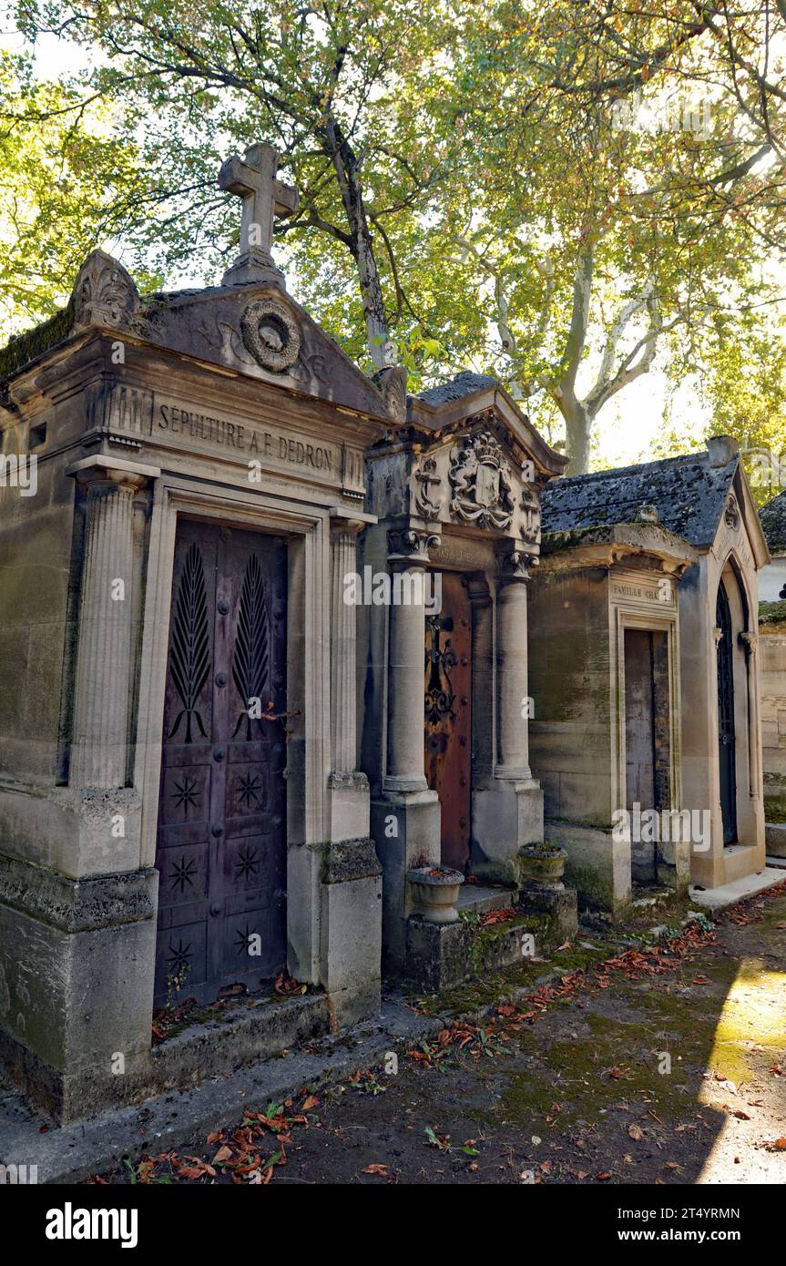 Une rangée de mausolées ombragés par des arbres dans le cimetière historique du Père Lachaise à Paris. Banque D'Images
