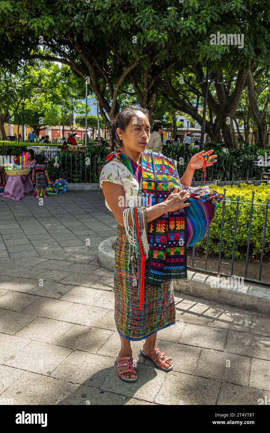 Guatemala, la Antigua - 20 juillet 2023 : en gros plan, jeune femme vêtue de vêtements colorés traditionnels tente de vendre des bijoux de couleur en plastique jake et sc Banque D'Images