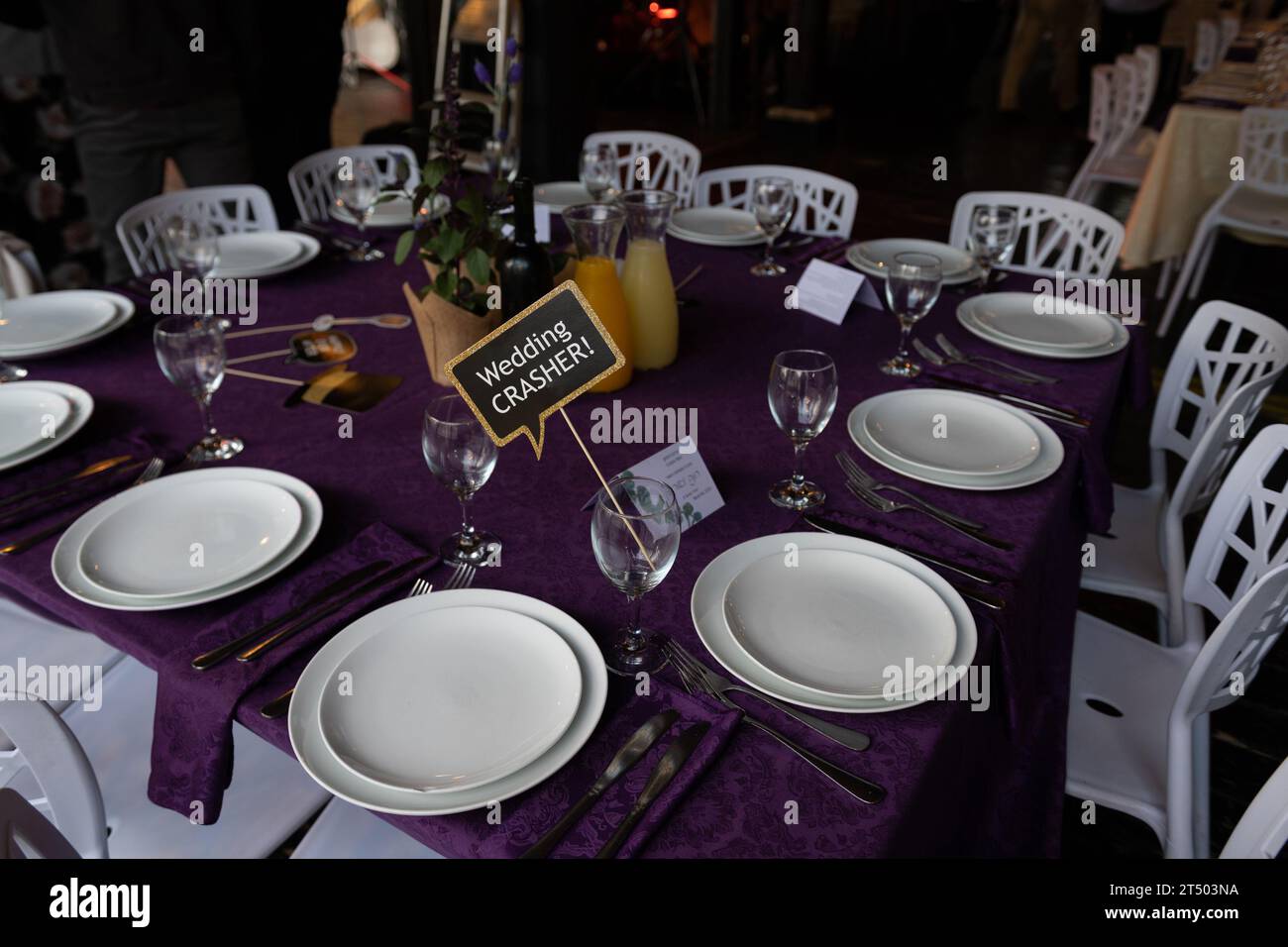 Un signe humoristique à un mariage tenant un siège pour un invité non invité connu sous le nom de crasher de mariage. Banque D'Images