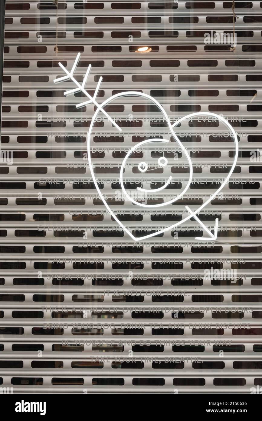 Un visage souriant cœur d'amour percé par la flèche de Cupidon posée contre une grille de sécurité en métal sur une vitrine de la vitrine Banque D'Images