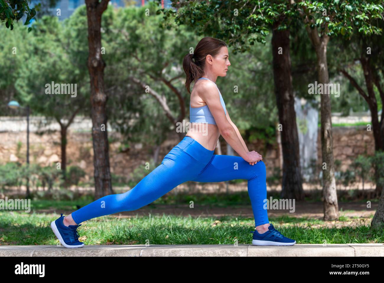 Femme sportive faisant l'exercice d'étirement des jambes à l'extérieur dans un parc Banque D'Images