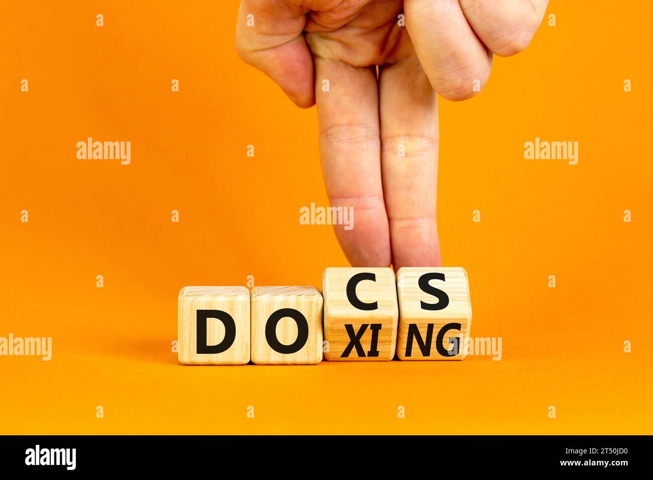 Symbole Docs ou doxing. Mots conceptuels Docs Doxing sur bloc de bois. Belle table orange fond orange. Main d'homme d'affaires. Documents d'affaires ou doxing Banque D'Images