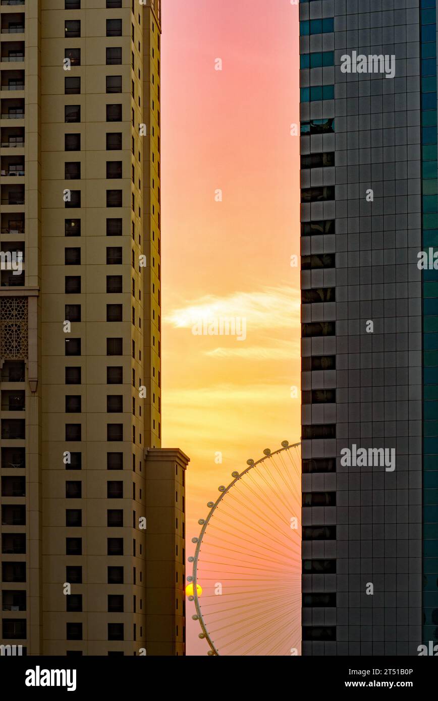 Dubaï, Émirats arabes Unis- 21 septembre 2023 : la silhouette stationnaire d'Ain Dubaï entre des blocs de tours résidentiels au Dubai Marine, une image de coucher de soleil. Banque D'Images