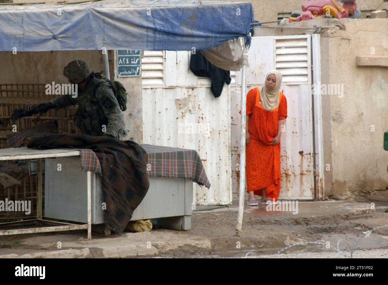 0707196031Q-005 CAMP Falcon, Irak (19 juillet 2007) - Une femme locale jette un coup d'œil pour voir comment des soldats du 1e peloton, la compagnie Charlie, de la 2e division d'infanterie, procèdent à l'inspection d'un sac considéré comme un engin piégé potentiel. Les soldats de la compagnie Charlie, 2e division d'infanterie, répondent fréquemment aux conseils des résidents locaux sur le placement d'engins piégés. US Navy Banque D'Images