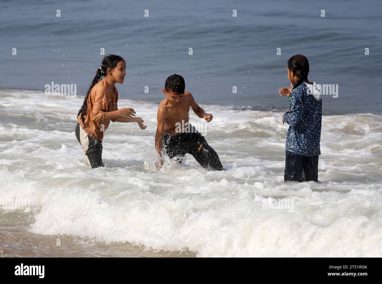 Des pêcheurs palestiniens vus sur leur bateau de pêche alors que d’autres se baignent et font leur lessive, se lavent à l’eau de mer en raison du manque d’eau douce et d’électricité, le long de la plage de Deir el-Balah, dans le sud de la bande de Gaza. Au milieu des combats en cours entre Israël et le groupe palestinien Hamas. Israël a pilonné Gaza dirigée par le Hamas le 29 octobre, dans une campagne aérienne et terrestre de plus en plus intense alors que l'ONU avertissait que l'ordre civil « commençait à s'effondrer » dans le territoire palestinien assiégé. Des milliers de civils, Palestiniens et Israéliens, sont morts depuis le 7 octobre 2023, après les militants palestiniens du Hamas Banque D'Images